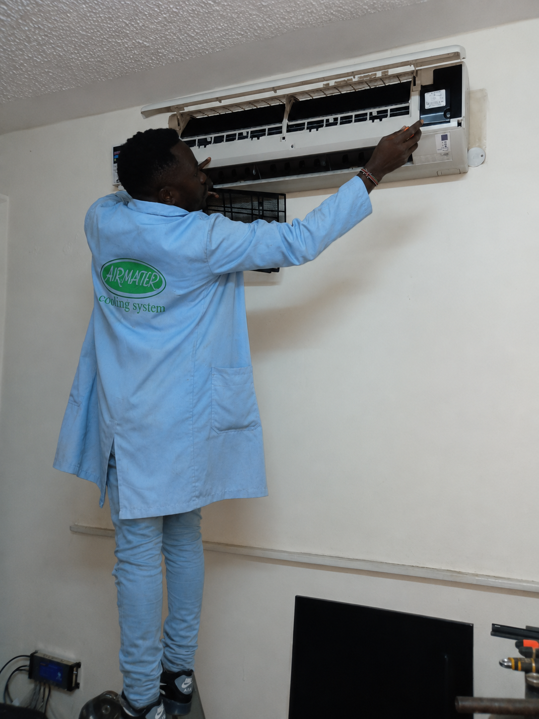 Airmaster technician servicing a wall-mounted air-conditioning unit